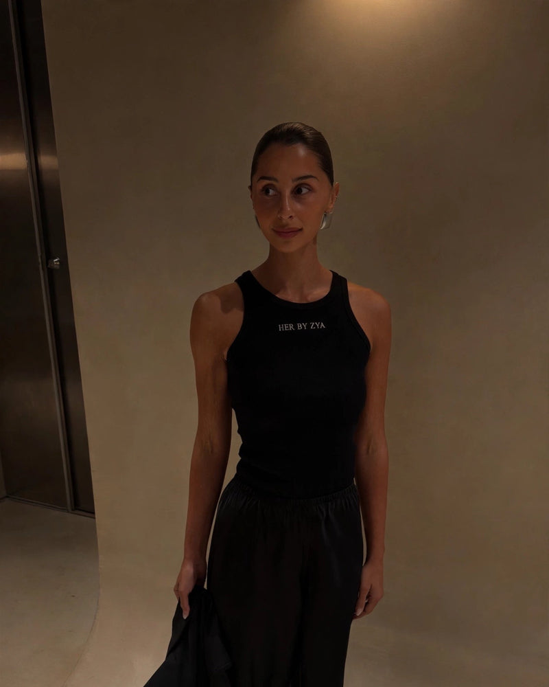 Full-length model photo of the black Her By Zya tank, framed from the top so the model's full head and tank are visible.